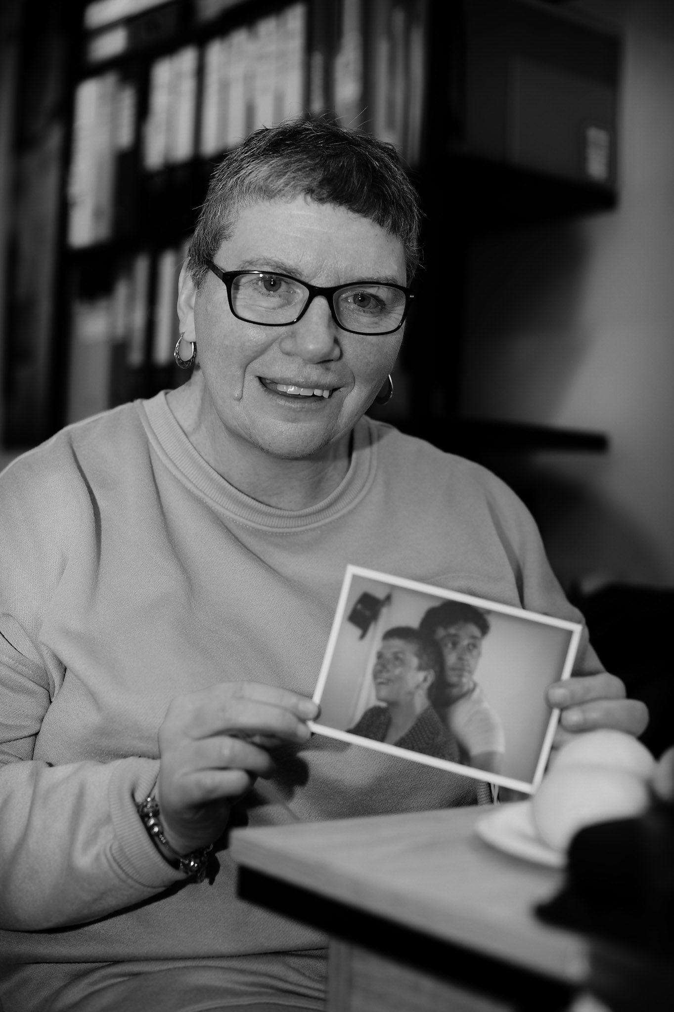 Black and white photo of Jackie holding a photo of her dancing with Daniel Hay Gordon
